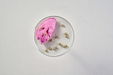 A minimalist composition featuring a delicate pink sorbet scoop resting on a silky smooth panna...