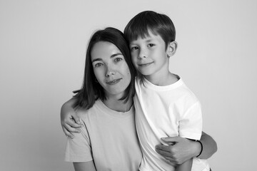 Closeup image of a son hugs his mother, they are sitting together. Black and white image.