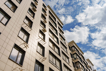 A multi-storey modern building against the background of the sky with clouds.