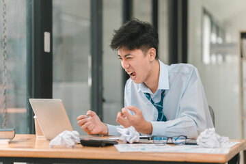Frustration at the Deadline: A young businessman struggles with a deadline, his frustration evident in his posture and expression. The crumpled papers and scattered documents contribute to a sense of 
