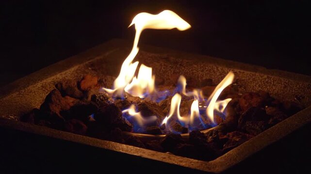 Close up of flickering flames in a fire pit, evoking warmth and relaxation in 4k slow motion 60fps