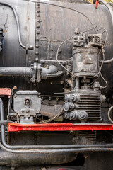 Detail of an old rusty steam train engine with intricate machinery and weathered metal components
