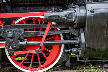 Detailed view of an old rusty steam train engine with red wheels and mechanical components