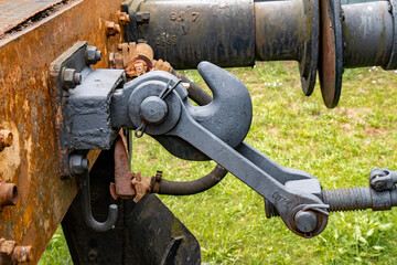 Detailed view of an old rusty steam train coupling mechanism in a green field