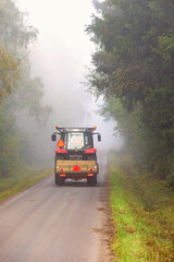 Tractor drives on a forest road a foggy autumn day