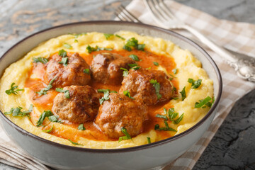 Fototapeta premium Fried meatballs with spicy sauce and corn polenta close-up in a bowl on the table. Horizontal