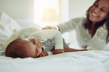 Baby, relax and bed with mother at house for play, family bonding and care together of childhood growth. Smile, child and fun with woman for support, love and trust of relationship development