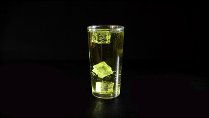 Lemonade with Rising Bubbles and Ice Cubes in Glass on a Black Background
