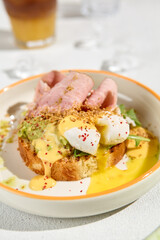 Gourmet Brioche with Ham, Poached Egg, and Hollandaise Sauce on White Plate