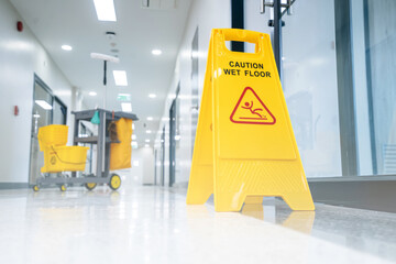 A Safety sign with caution phrase. Happy young housekeeper mopping the floor with a mop and...