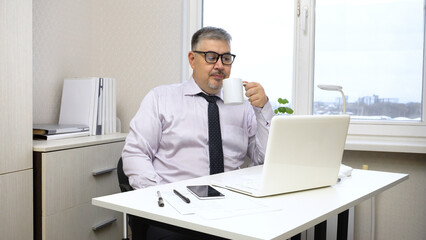 Businessman Drinking Tea and Working on Computer in Office