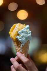 Close up hand of a person holding ice cream cone with blurred background
