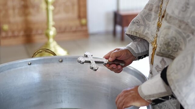 The priest blesses the water on the baptismal font in the church. 