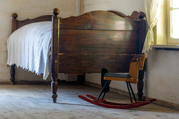 Old bed in the bedroom with a rocking horse