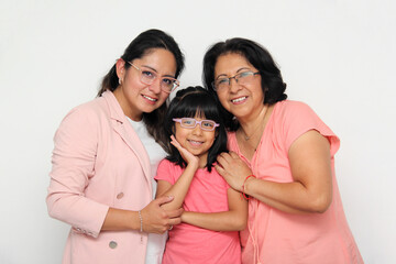 Three generations of brunette Latina women with glasses, grandmother, mom and daughter hug each...