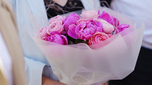 A delicate and beautiful bouquet of pink peony roses in a woman's hands. 
