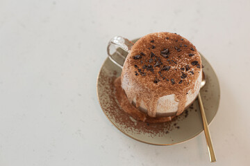 Iced coffee with frothy cream overflowing chocorate topping with powder.