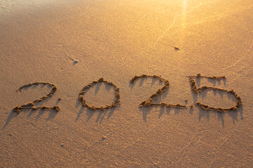 Written text 2025 on the sea beach at sunrise.