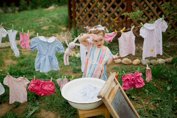 little girl playing  in a garden, washing clothes