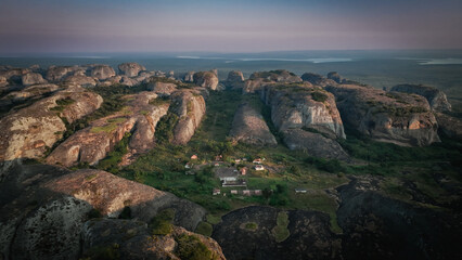Fototapeta premium Aerial view of the Pedras Negras Mountains showcasing lush greenery and remote settlements in Angola during twilight