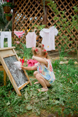 little girl playing  in a garden, washing clothes