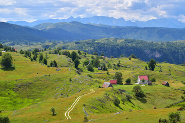 Path leading to few houses in picturesque Alps mountain landscape