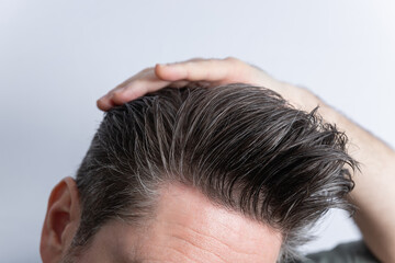 Close-up of an unrecognizable man combing his toupee with his hand. Styling and hair care concept