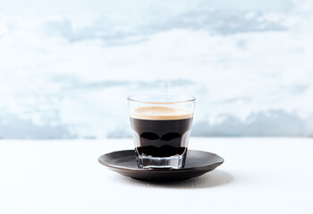 Coffee in glass cup on bright wooden background. Copy space.