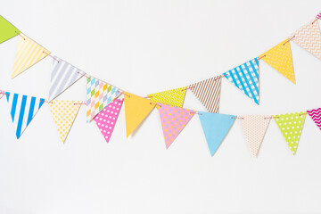 Two decorative colorful pennant garlands on white wall background for birthday celebration,...