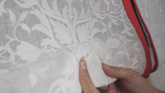 Woman's hands touching white lace roman blind