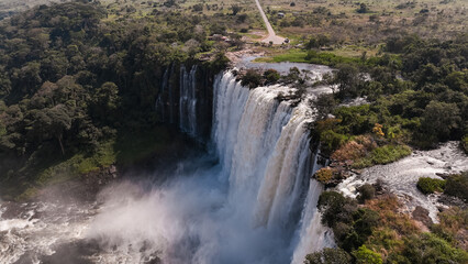 Kalandula Waterfall cascading down rocky cliffs in Angola surrounded by lush greenery under a clear...