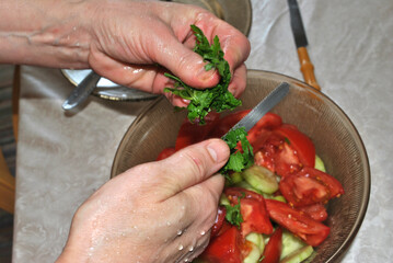 Woman hands preparing salad closeup, knife cutting parsley for a tomato salad