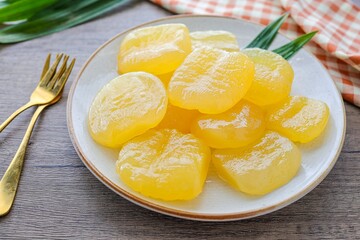 Toddy palm in syrup in a white ceramic  with golden fork plate on wooden background , thai dessert , thai called luk tan chuem