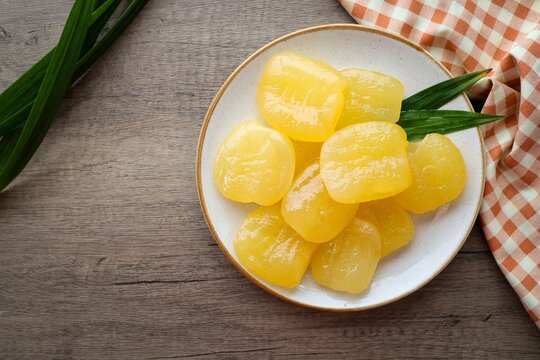 Toddy palm in syrup in a white ceramic  with golden fork plate on wooden background , thai dessert , thai called luk tan chuem