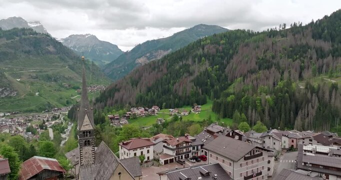 Aerial view of the alpine rural landscape of Rocca Pietore in Italy. Spires of the cathedral on the slopes of the Dolomite Alps in beautiful historical architecture. High quality 4k footage