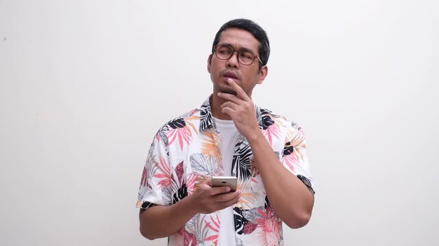 A man try to remember something when texting using mobile phone