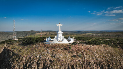 Statue of Christ stands majestically on a hillside in Lubango, Angola, overlooking the landscape during daylight © Dave