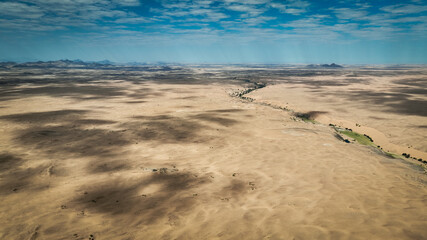 Aerial view of the vast wild landscape of Angola showcasing arid terrain and distant mountains under a blue sky