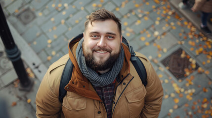 Fototapeta premium Joyful man wearing a warm jacket, with a backpack, enjoying a beautiful autumn park scenery