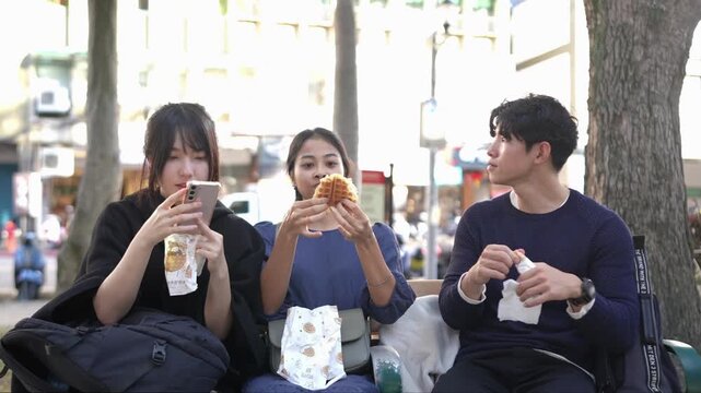A slow-motion video capturing a young Taiwanese woman and a South Asian woman walking and chatting amiably on a public road near a university in Taipei's Da'an District.