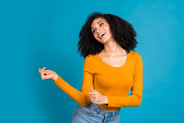 Photo portrait of attractive young woman dancing look empty space dressed stylish yellow clothes isolated on blue color background