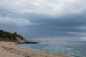 Beautiful coastal landscape in a sandy beach under stormy clouds in Costa Brava, Catalonia