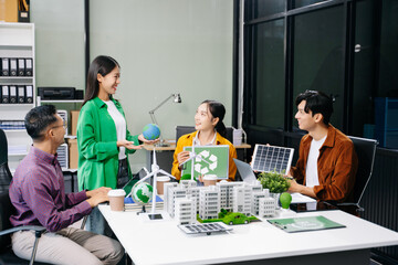 Group of diverse multiethnic businesspeople standing neare table looking at model of building from residential project. Green business company