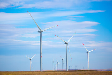 Fleet of power generators in motion. The blades of the wind farm rotate against the sky. The...