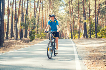 Naklejka premium woman cyclist rides in the forest on a bike.
