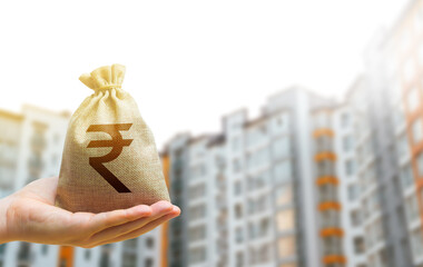 Indian rupee money bag against the background of modern high-rise buildings. Investing in the...