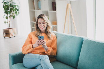 Obraz premium Portrait of nice young girl sit couch hold device wear orange clothes modern interior flat indoors