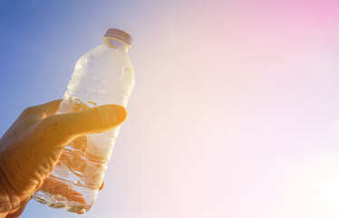 Plastic bottle in hand on blue sky background. Plastic recycling and waste collection. Plastic...