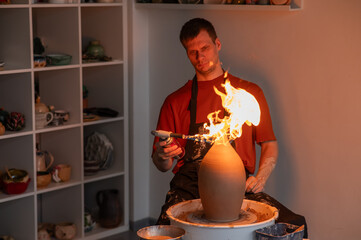 A potter burns a jug with a gas burner on a potter's wheel. 