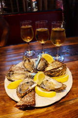 seafood and white wine in a glass. plate with oysters, lemon and bread with butter on a wooden table